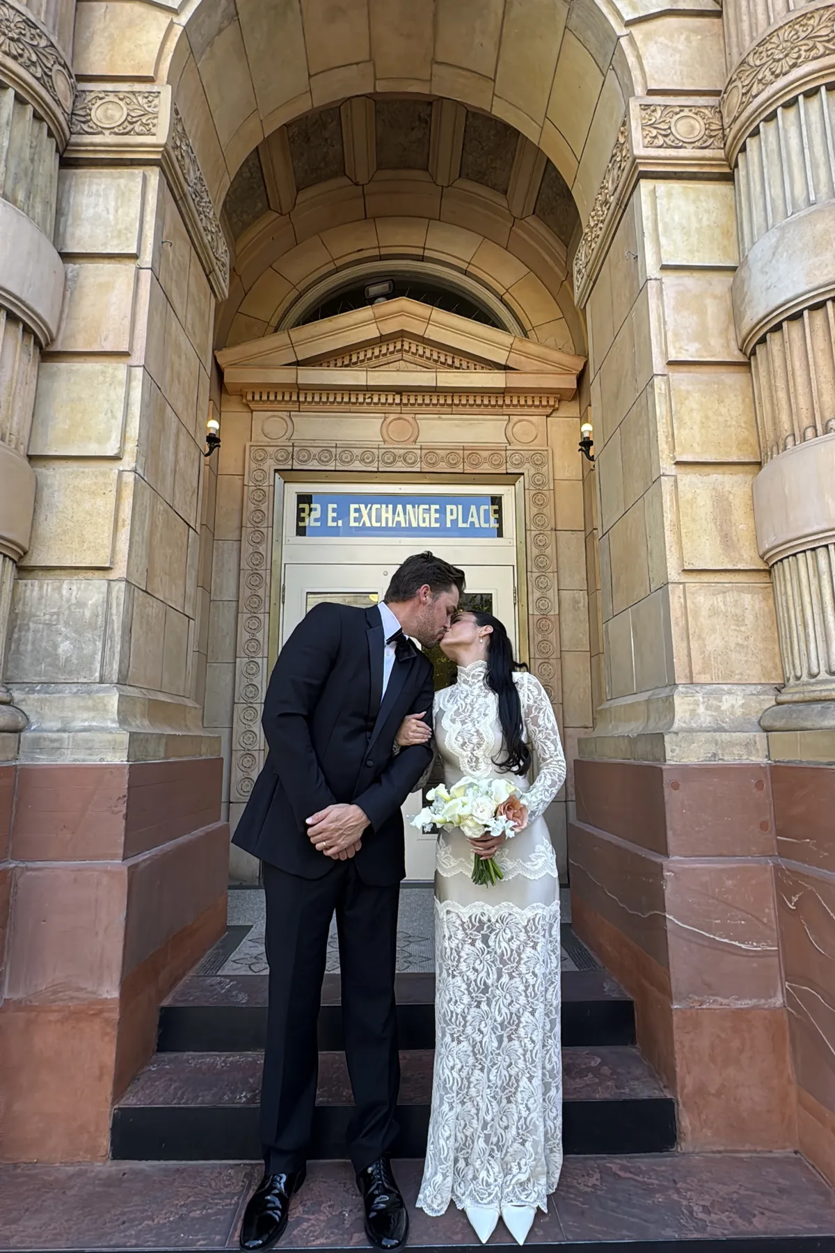 Bride and groom kissing at the doors of a historic downtown building.