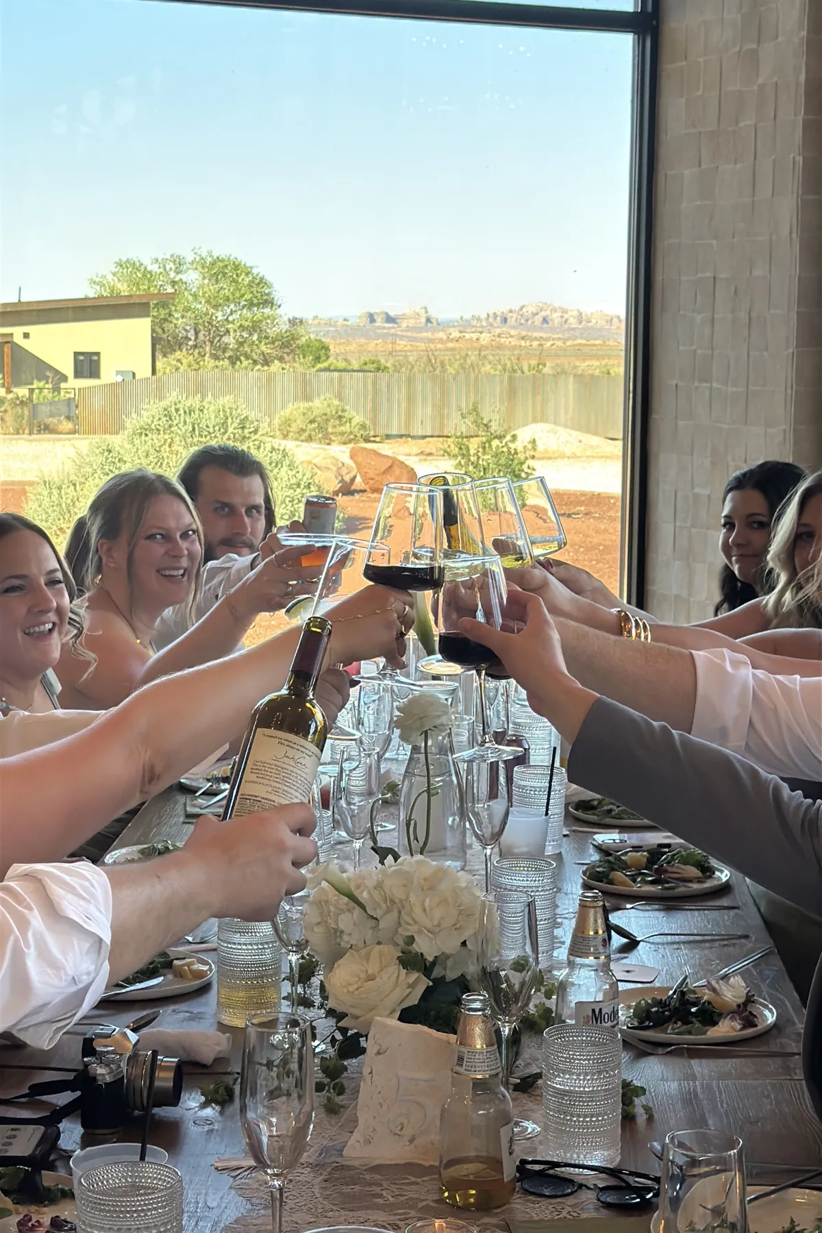 Wedding guests raising glasses for a toast at the reception table.