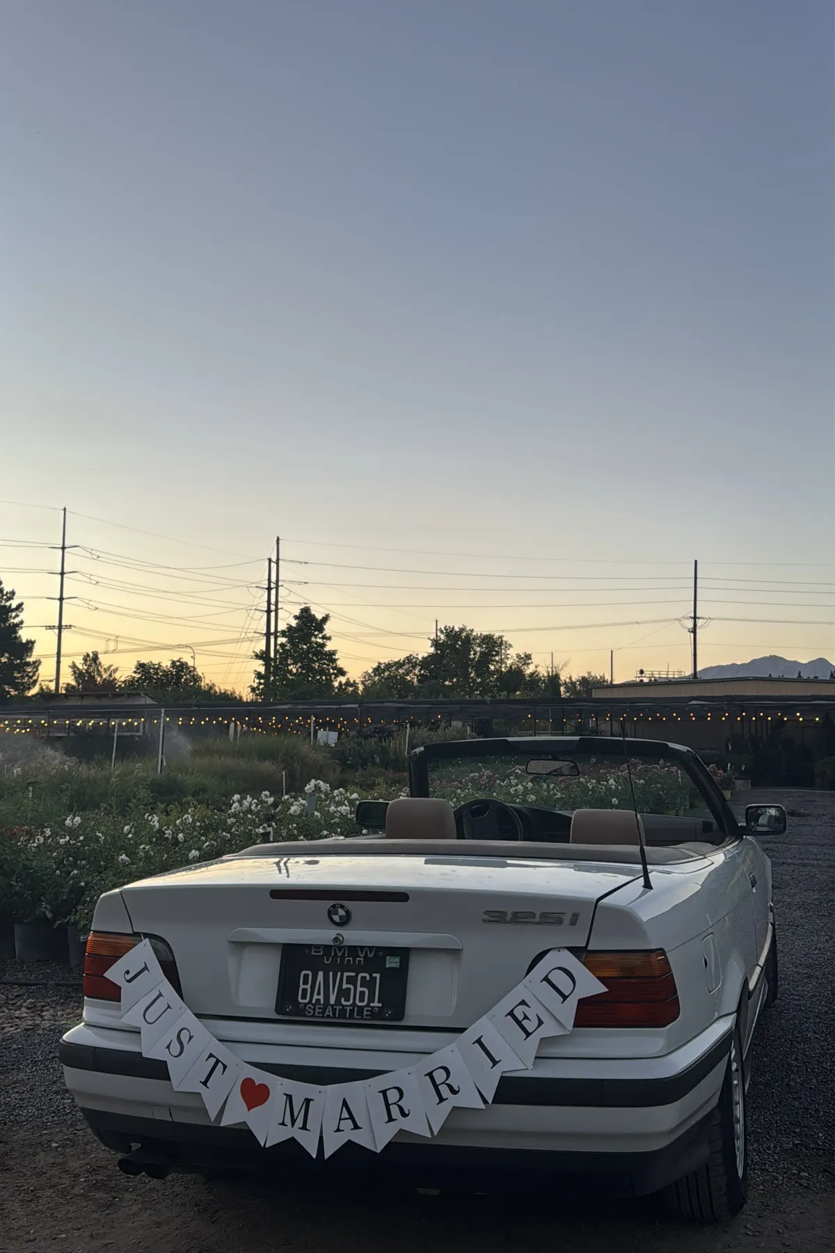Classic convertible send-off car parked under string lights at dusk.