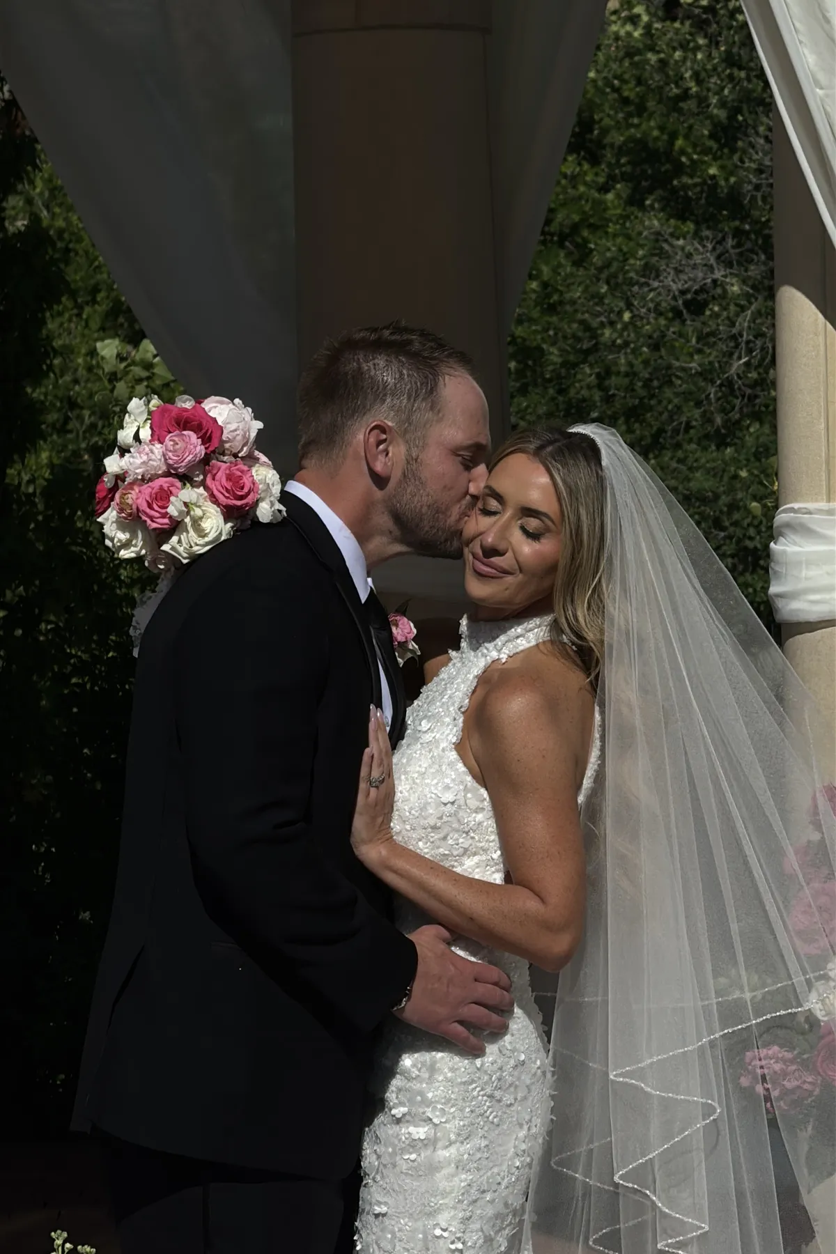 First kiss at a ceremony framed by pink and white florals.