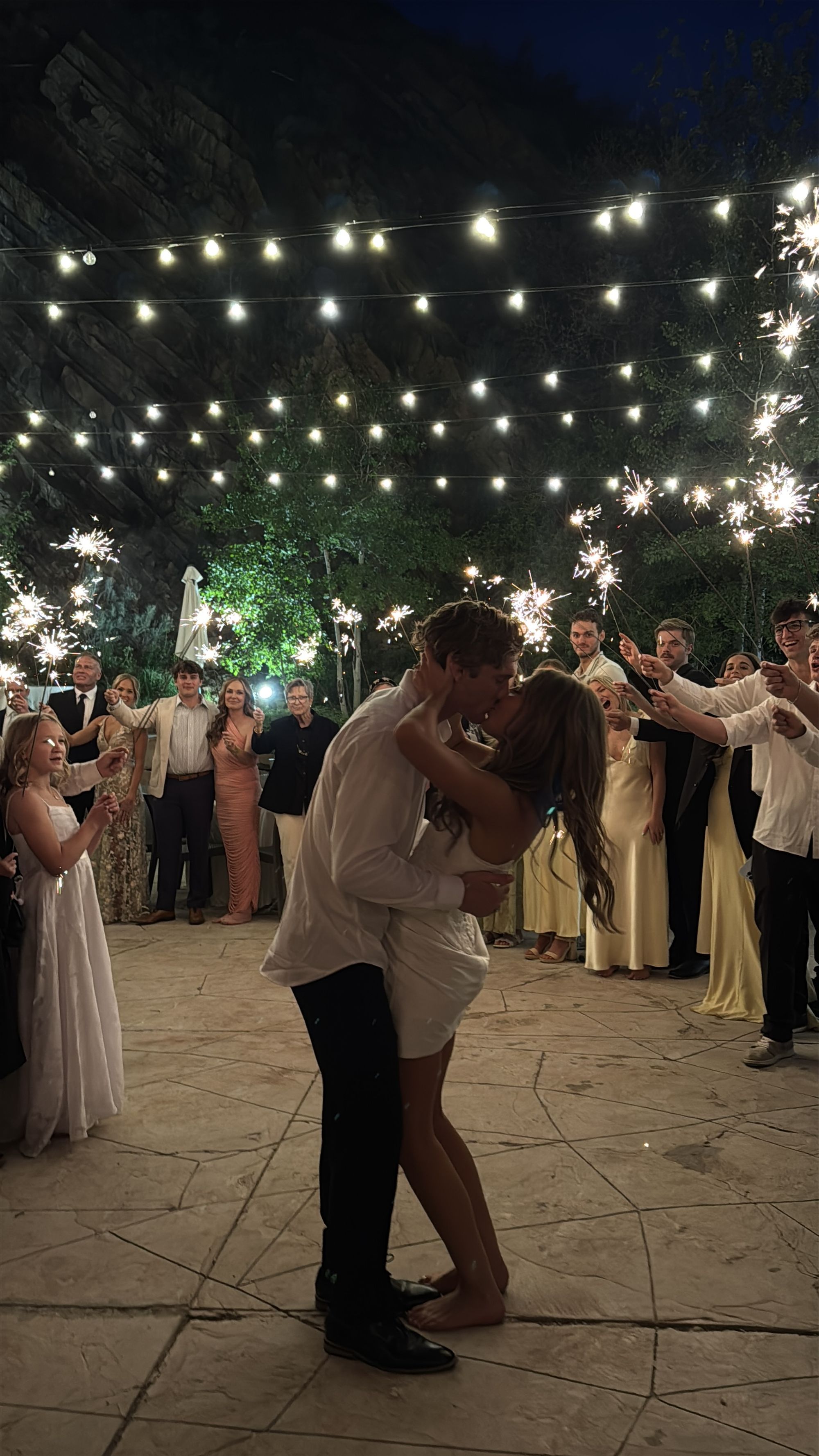 Couple kissing on the dance floor surrounded by sparklers.