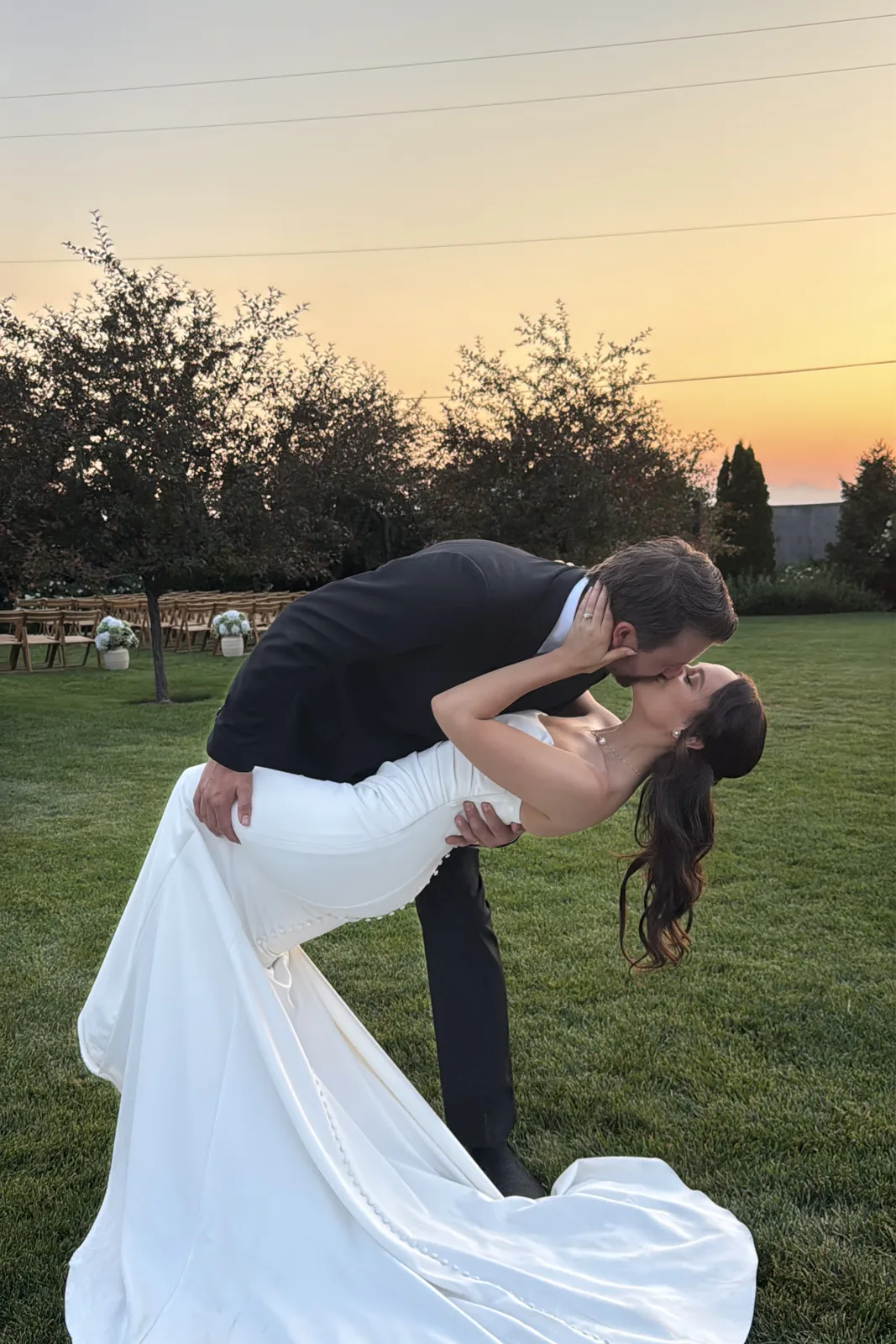 Groom dipping the bride for a kiss at sunset.